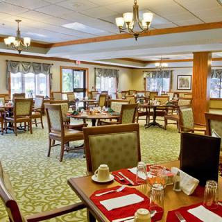 An elegantly set dining room with neatly arranged tables and chairs, illuminated by chandeliers.