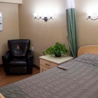 A cozy bedroom with a bed, leather chair, and a nightstand adorned with a plant.