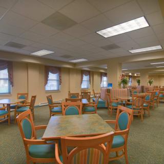 A spacious dining area with multiple tables and chairs arranged neatly under ceiling lights.