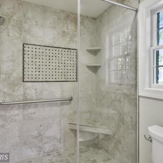 A modern bathroom with a glass-enclosed shower and tiled walls.
