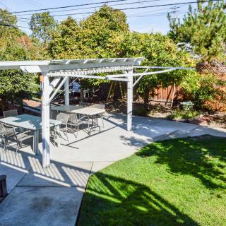 A sunny backyard with a pergola and outdoor seating area.
