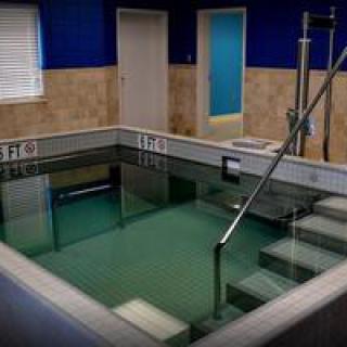 An indoor therapeutic swimming pool with stairs and handrails.