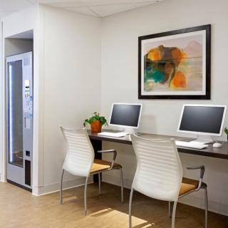 A modern office workspace featuring two computers and chairs, with abstract artwork on the wall.