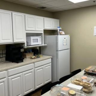 A typical office break room with a kitchen setup, including a microwave and fridge.