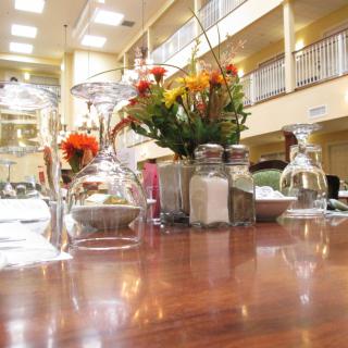 A well-set restaurant table with glassware, flowers, and salt and pepper shakers in an elegant dining area.