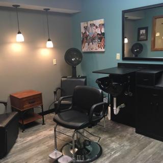 A cozy hair salon interior featuring a styling chair, mirrors, and modern lighting.