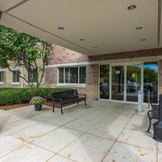 A welcoming entrance featuring benches and landscaped greenery.