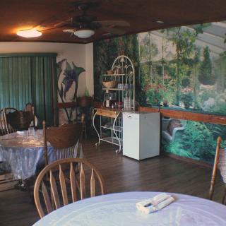 A cozy dining area with wooden furniture and a nature-themed wall mural.