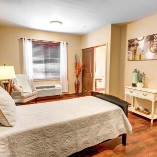 A cozy bedroom with a neatly made bed, wooden flooring, and stylish decor.