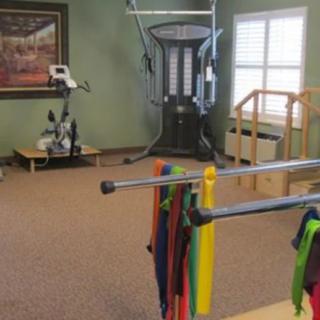 A room equipped with exercise machines and therapy bands, likely used for fitness or rehabilitation purposes.
