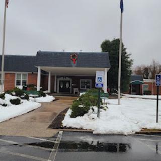 A view of a building entrance with snowy surroundings and flags standing in front.