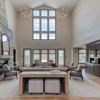 A luxurious and modern living room with high ceilings, large windows, and elegant chandeliers.