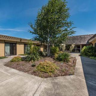A well-maintained courtyard with landscaping and a central tree, surrounded by buildings under a clear blue sky.