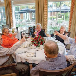 A group of elderly people enjoying a meal together at a decorated dining table.
