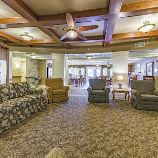 Cozy living room with sofas and armchairs, featuring a ceiling fan and warm lighting.