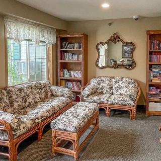 A cozy living room with patterned couches, bookshelves, and a mirror.