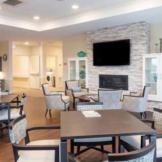 A modern living room with dining area, featuring a stone fireplace and wall-mounted television.