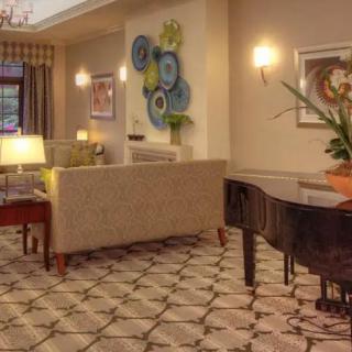 A cozy living room with a grand piano, elegant furniture, and decorative artwork.