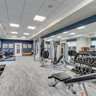 A modern gym with various exercise equipment and free weights.