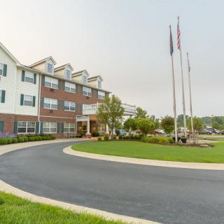 An exterior view of a hotel with well-maintained landscaping and multiple flags at the entrance.