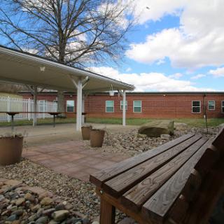A peaceful outdoor courtyard with benches and a view of a brick building under a cloudy sky.