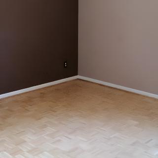 A minimalist empty room with two-tone brown walls and a light hardwood floor.