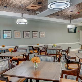 A cozy dining area with neatly arranged tables and comfortable chairs, featuring modern lighting and wall decorations.