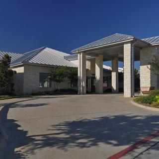 A modern building with a prominent entrance and surrounding landscaping.