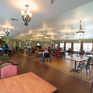 A spacious dining hall with tables and chairs, filled with people enjoying a meal.
