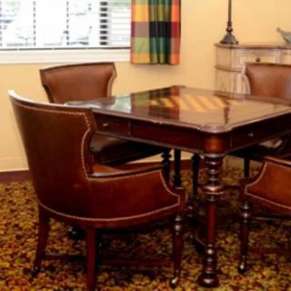A classic wooden table with leather chairs in an elegant room setting.