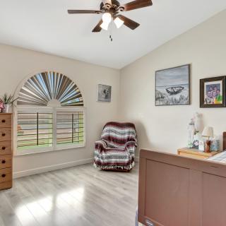 A cozy bedroom with a wooden floor, featuring a chair, dresser, and decorative wall art.