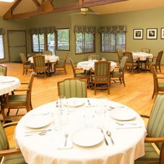 An elegantly set dining room with multiple tables and chairs, ready for guests.