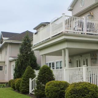 A modern house featuring a spacious balcony and well-manicured shrubs.