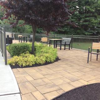 A serene outdoor seating area featuring a well-maintained patio, lush greenery, and comfortable chairs.