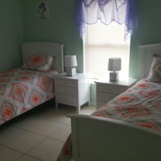 A cozy bedroom with twin beds, decorated with floral bedding and soft green walls.