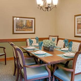 A traditional dining room setup with a wooden table, upholstered chairs, and decorative place settings.