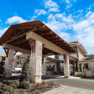 A modern building entrance featuring wooden and stone architecture under a blue sky.