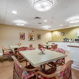 A cozy dining area with neatly arranged tables and chairs, adorned with simple decor and warm lighting.