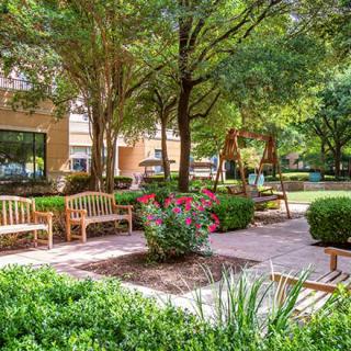A serene garden with benches, surrounded by greenery and trees.