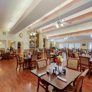 A spacious dining area with neatly arranged tables and chairs, featuring elegant decor and ample lighting.