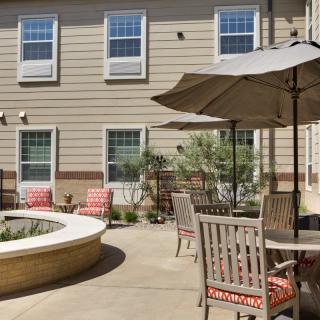 An outdoor patio area with chairs, tables, and umbrellas adjacent to a building.