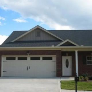 A suburban brick house with a double garage and a small lawn.