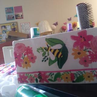 A beautifully decorated box with floral patterns and a bee design, surrounded by craft supplies.