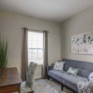 A cozy living room with a desk, sofa, and minimalist decor.