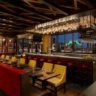 A modern restaurant interior with a bar and seating area, featuring stylish lighting.