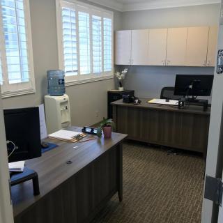 A neat and organized office space with two desks, computers, and a water dispenser.