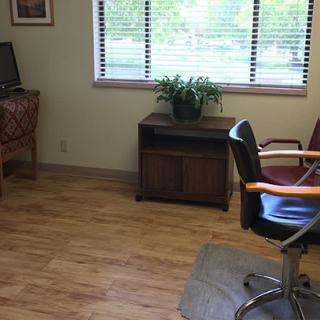 A small office space with a desk, chair, and plant by the window.