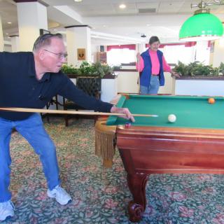Two people playing a game of pool indoors.