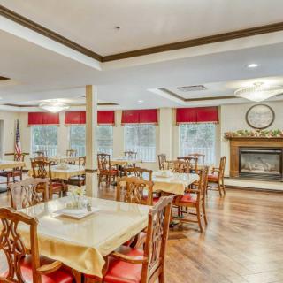 A spacious and elegant dining room with wooden tables and chairs, featuring a fireplace and large windows.