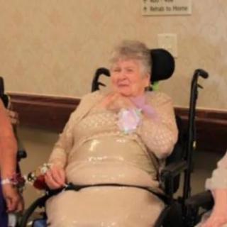 An elderly woman in a wheelchair at a social event.